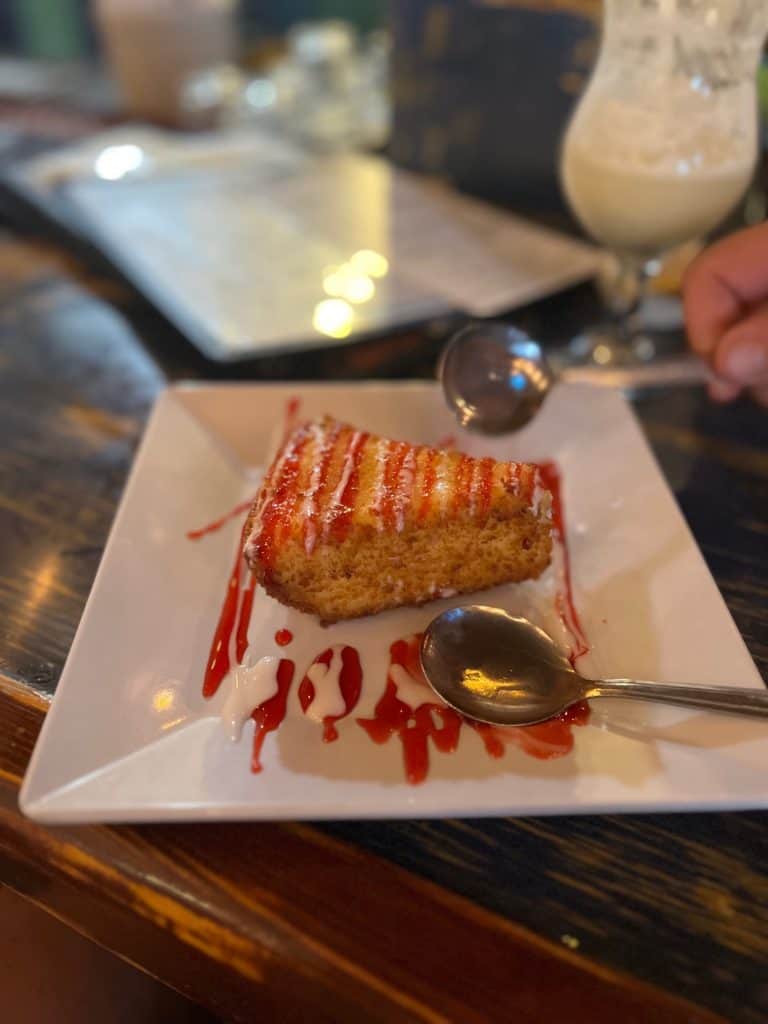 Picture of a triangle of fried key lime pie with breadcrumbs and raspberry drizzle on a plate with two spoons