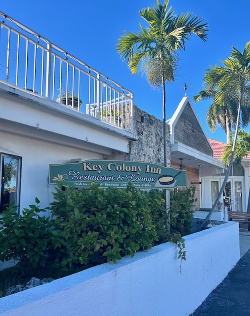 exterior of a white building with palm trees out from - the Key Colony Inn in Marathon