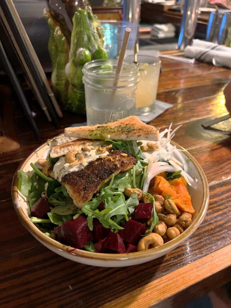 Green salad topped with beets fish cashews and sprouts