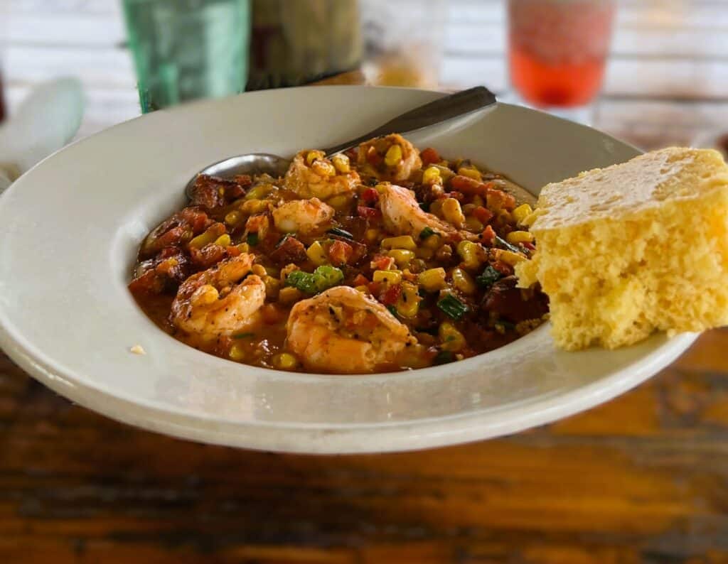 a plate of shrimp and grits with cornbread on the side