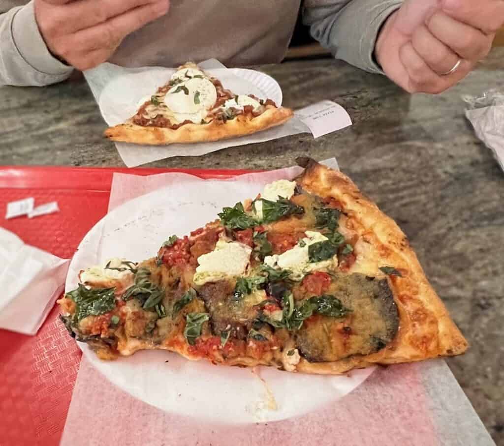 two slices of pizza with heavy toppings on a tray on a table 