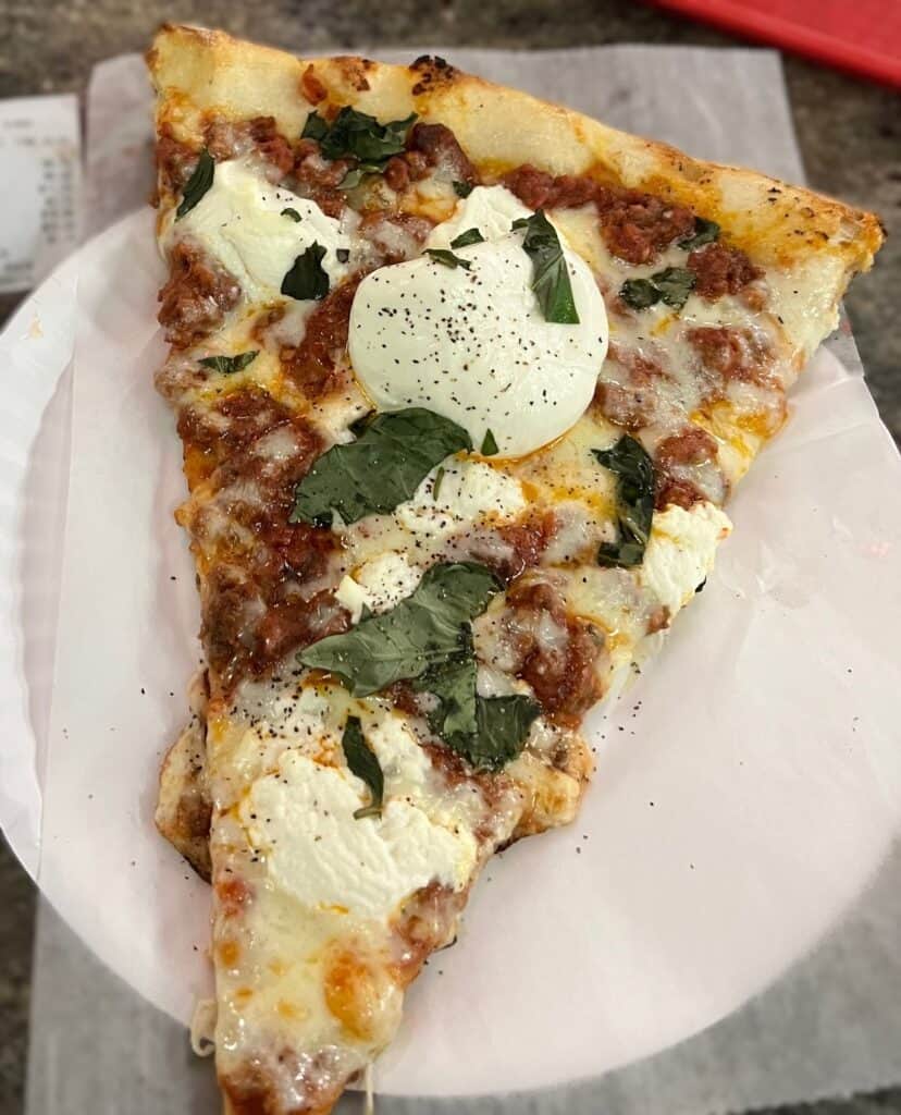 Slice of pizza with scoops of burratta