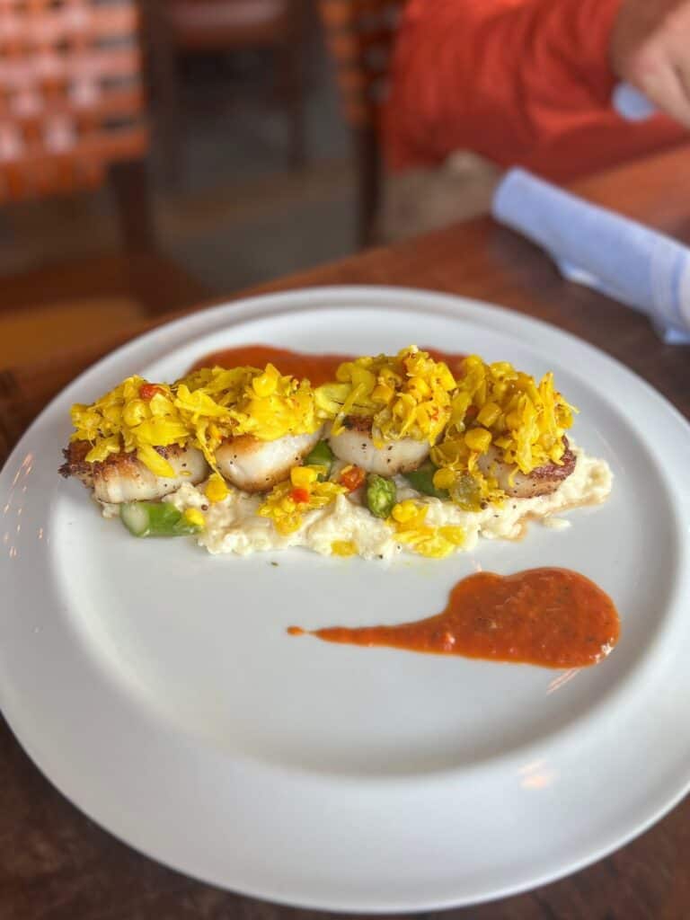 plate of scallops topped with topped with corn chow chow and a red pepper sauce