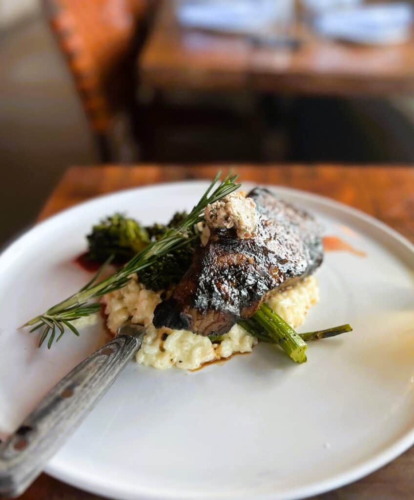 image of steak on top of risotto with a spring of rosemary