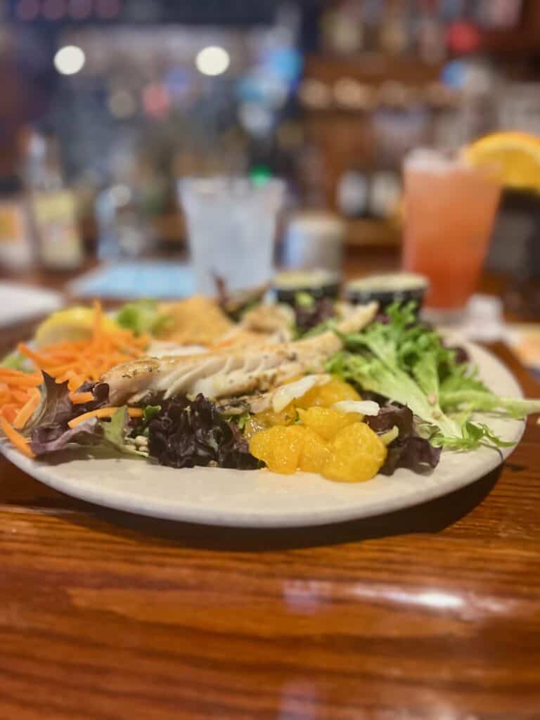 a plate salad with oranges, carrots and fish