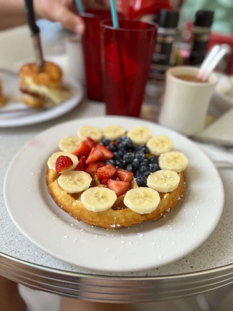 waffle topped with bananas, strawberries and blueberries