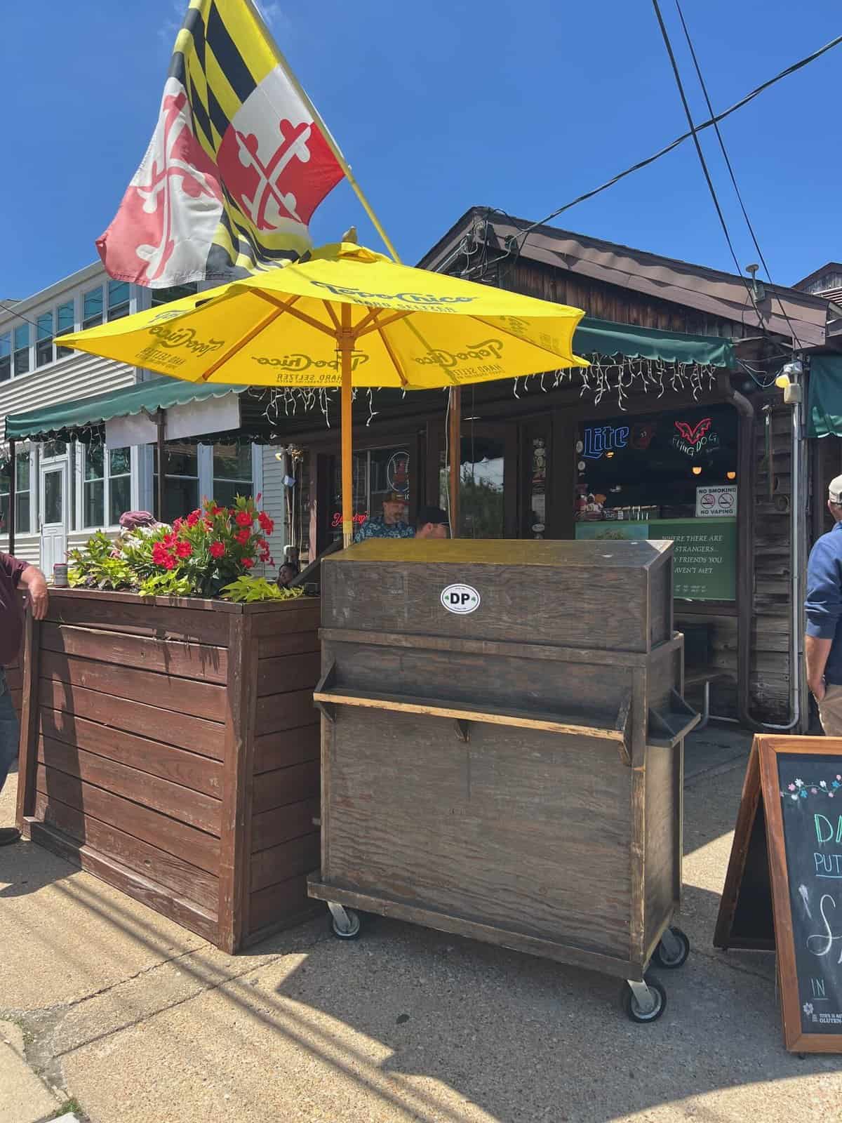 Outside view of Davis' Pub showing the brown exterior and yellow umbrella in the outdoor seating area