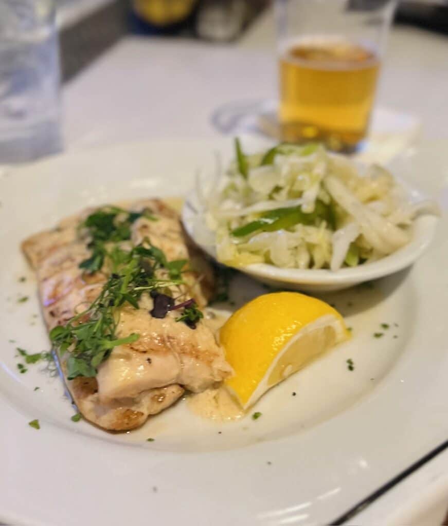 Rockfish with capers and cabbage slaw with lemon on a white plate